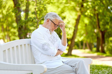 老,退休人们的体贴的老人戴着眼镜,坐夏季公园的长凳上坐夏季公园的体贴的老人背景图片
