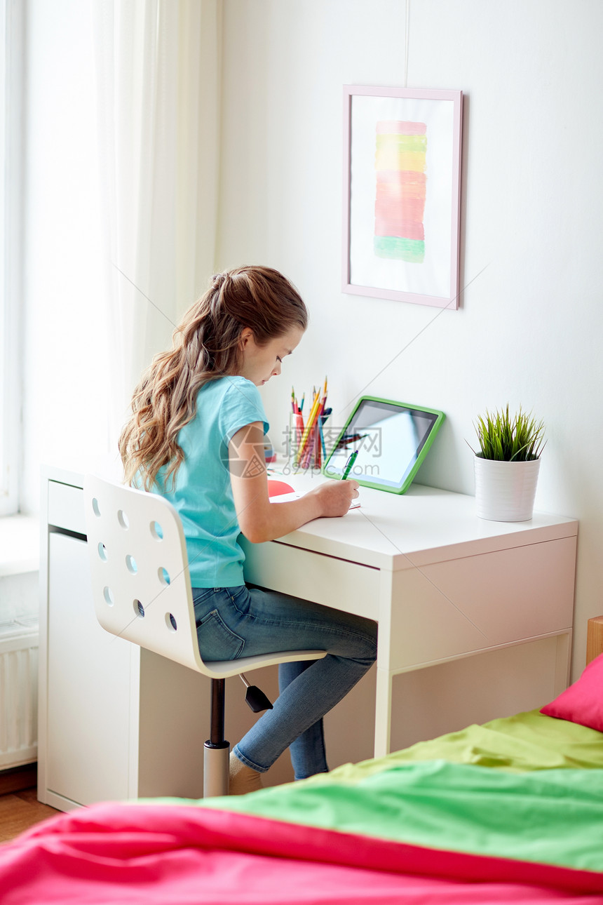 人孩子教育理念快乐的女孩用平板电脑家里写笔记本女孩家里用平板电脑写笔记本图片