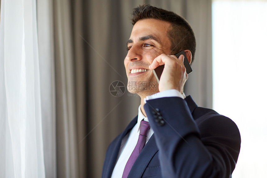 商业,人沟通快乐的微笑商人打电话酒店房间办公室的智能手机商人酒店房间打电话给智能手机图片