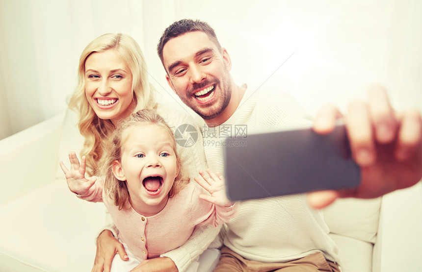 假期,技术人的快乐的家庭坐沙发上,家里用智能手机自拍家人家用智能手机自拍图片
