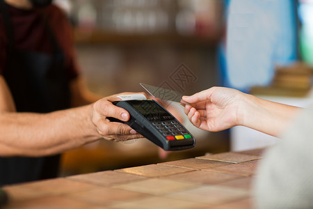 销售时点情报系统现代技术人的男人酒保与支付终端客户的手与信用卡咖啡厅酒吧手支付终端信用卡背景