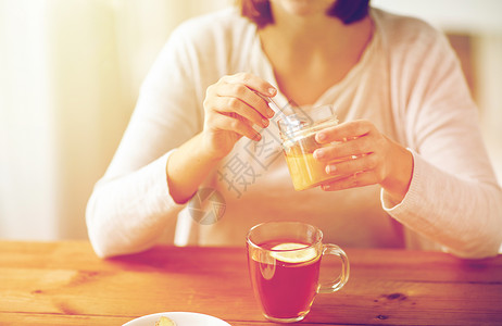 健康传统医学民族科学木桌上用柠檬蜂蜜喝茶的病妇靠近生病的女人喝蜂蜜茶图片