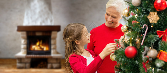 寒假,家庭人的快乐的祖母孙女带壁炉的家庭房间里装饰诞树诞树上的祖母孙女图片