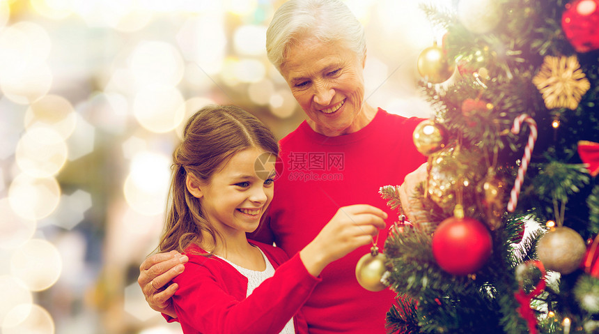 寒假,家庭人的快乐的祖母孙女灯光背景下装饰诞树诞树上的祖母孙女图片