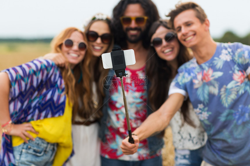 暑假,技术人的微笑的轻嬉皮朋友戴着太阳镜,用智能手机农村自拍杆上拍照嬉皮士朋友智能手机自拍棒图片
