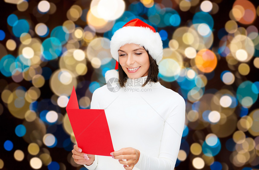 诞节,假日人们的快乐的微笑女人诞帽阅读贺卡的灯光背景快乐的女人读诞贺卡图片