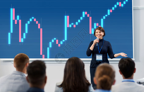金融讲座商业,经济人的微笑的女商人金融家与外汇图表投影屏幕麦克风与学生会议演讲讲座出席商务会议讲座的群人背景