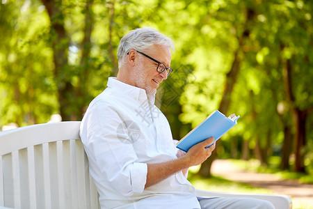 老,退休人们的快乐的老人读书坐长凳上的夏季公园快乐的老人夏天公园看书图片