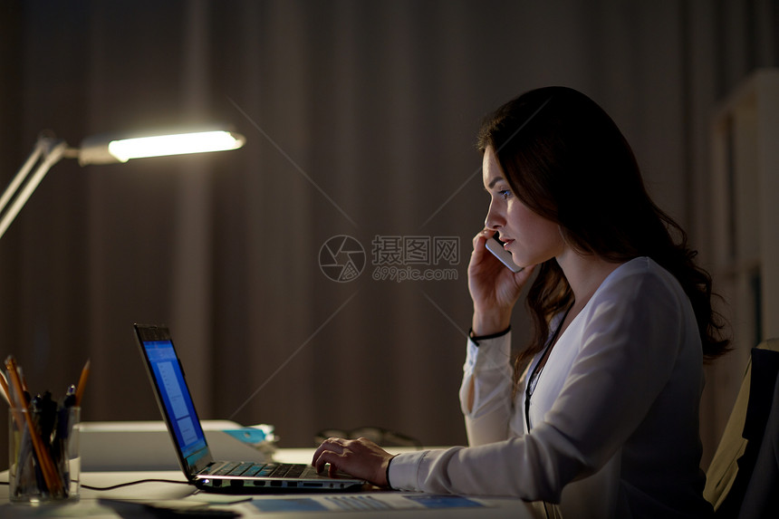 商业,技术,过度工作,截止日期人的女人带着笔记本电脑夜间办公室打电话给智能手机笔记本电脑的女人办公室打电话给智图片