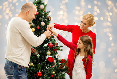 家庭,假期人的快乐的母亲,父亲女儿灯光背景下装饰诞树诞树上的母亲父亲女儿图片