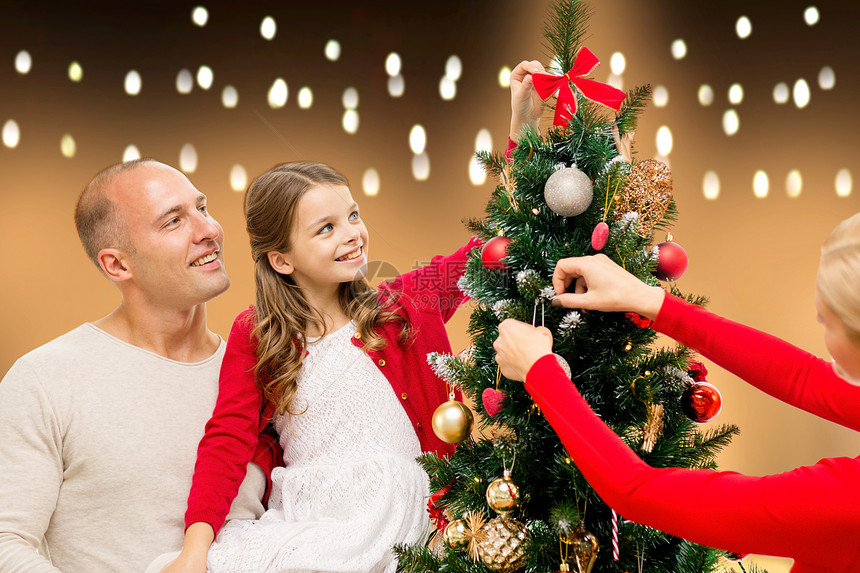 家庭,假期人的快乐的母亲,父亲女儿灯光背景下装饰诞树幸福的家庭家里装饰诞树图片