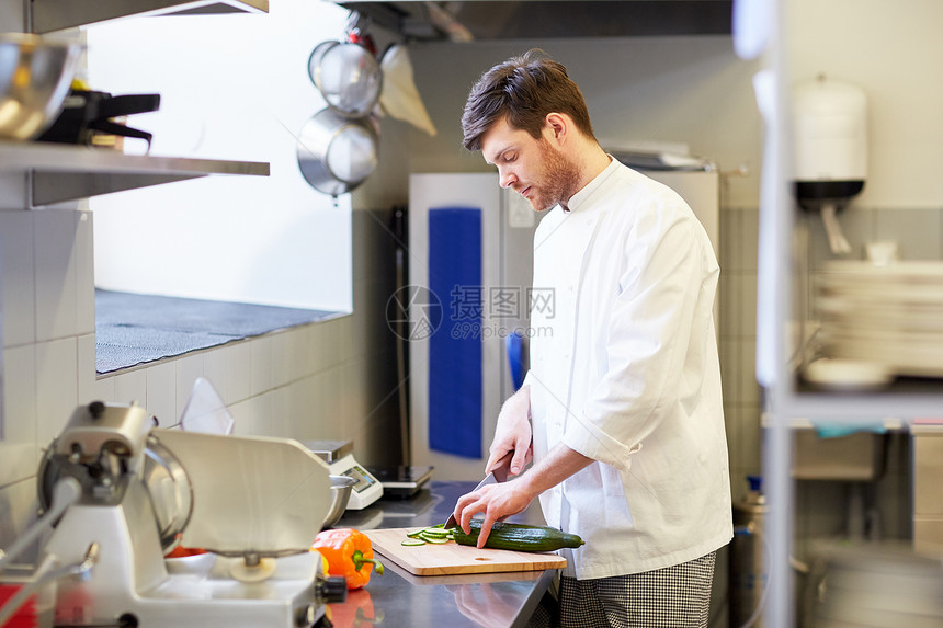 烹饪食物,职业人的快乐的男厨师用刀切黄瓜餐厅厨房的砧板上饭快乐的男厨师餐厅厨房烹饪食物图片