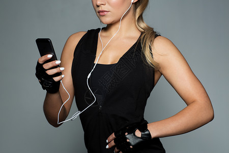 运动,健身,技术人的轻妇女与智能手机耳机听音乐健身房带智能手机耳机的女运动员背景图片