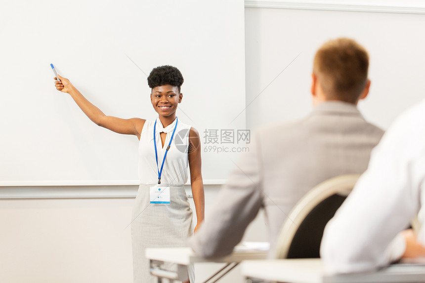 商业,教育人的微笑的非裔美国女商人讲师与标记些东西屏幕上的学生会议演示讲座出席商务会议讲座的群人图片