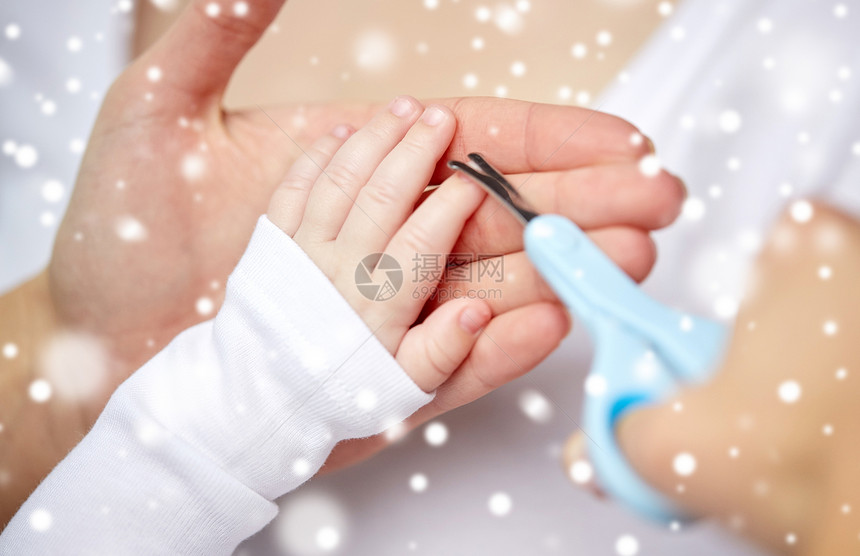 母亲人儿童保育的用剪刀把婴儿指甲剪雪地上用剪刀修剪婴儿指甲手图片