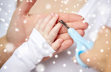 母亲人儿童保育的用剪刀把婴儿指甲剪雪地上用剪刀修剪婴儿指甲手图片