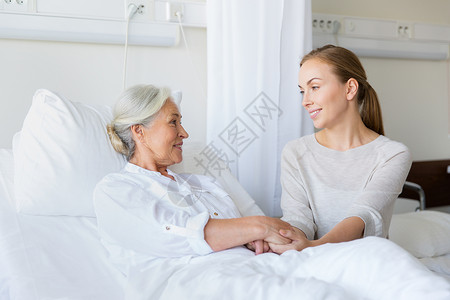 医学,家庭,医疗人的女儿拜访欢呼她的母亲躺医院病房的床上女儿医院看望迈的母亲背景图片