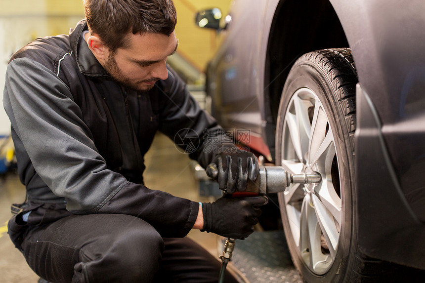 汽车服务,维修,维护人的汽车技工与电动螺丝刀更换轮胎车间汽车机械师与螺丝刀更换汽车轮胎图片