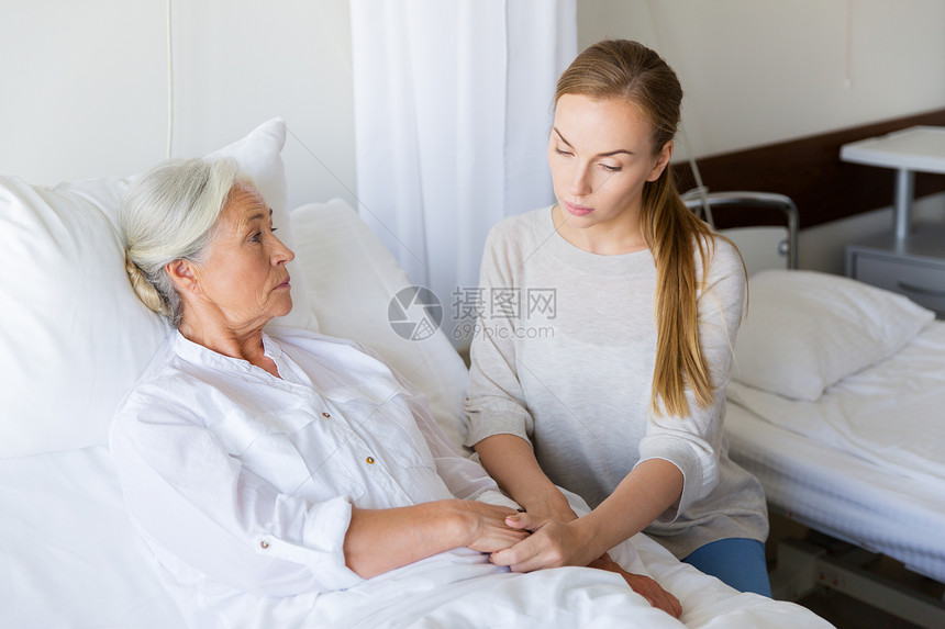 医学,家庭,医疗人的女儿拜访欢呼她的母亲躺医院病房的床上女儿医院看望她的老母亲图片