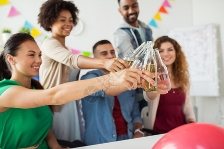 亚洲的队公司,庆祝假日快乐的同事办公室聚会上用含酒精的饮料碰瓶子快乐的队办公室聚会上喝酒庆祝背景