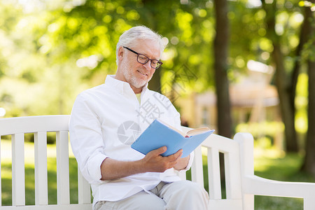 老,退休人们的快乐的老人读书坐长凳上的夏季公园快乐的老人夏天公园看书图片