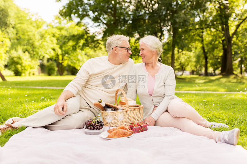 老,假期,休闲人们的快乐的老夫妇与野餐篮子坐毯子夏季公园快乐的老夫妇夏天的公园野餐图片
