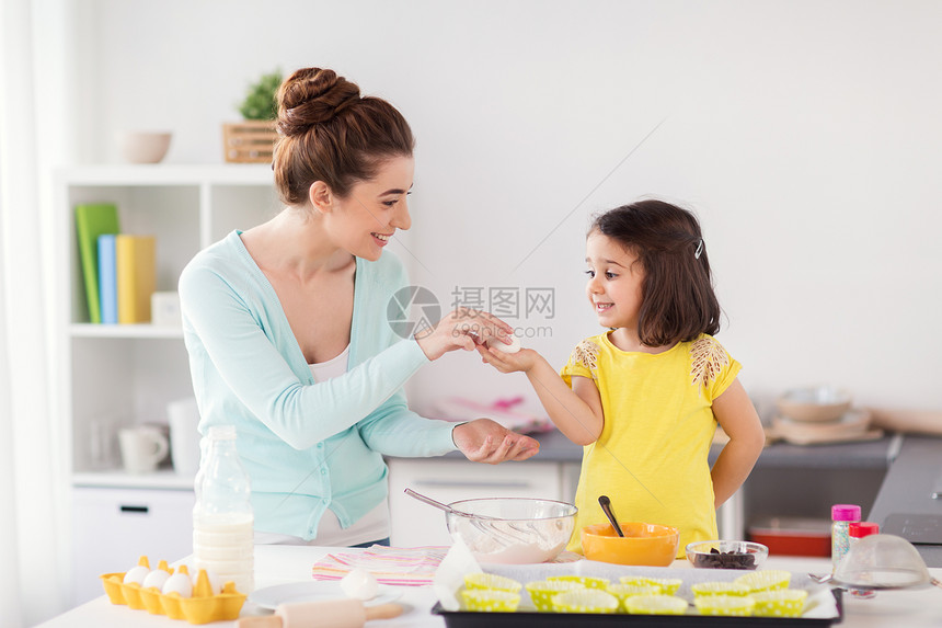 家庭,烹饪,烘焙人们的快乐的母亲小女儿着鸡蛋,家里的厨房纸杯蛋糕快乐的母女家烘焙图片