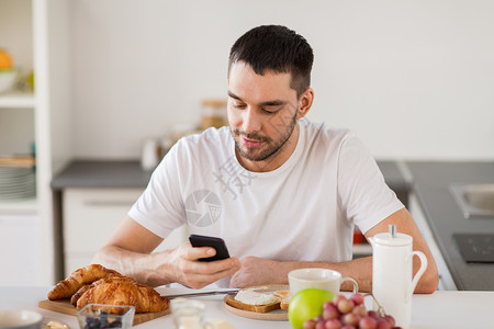 技术,饮食人的快乐的人与智能手机家里吃早餐带智能手机的男人家吃早餐图片