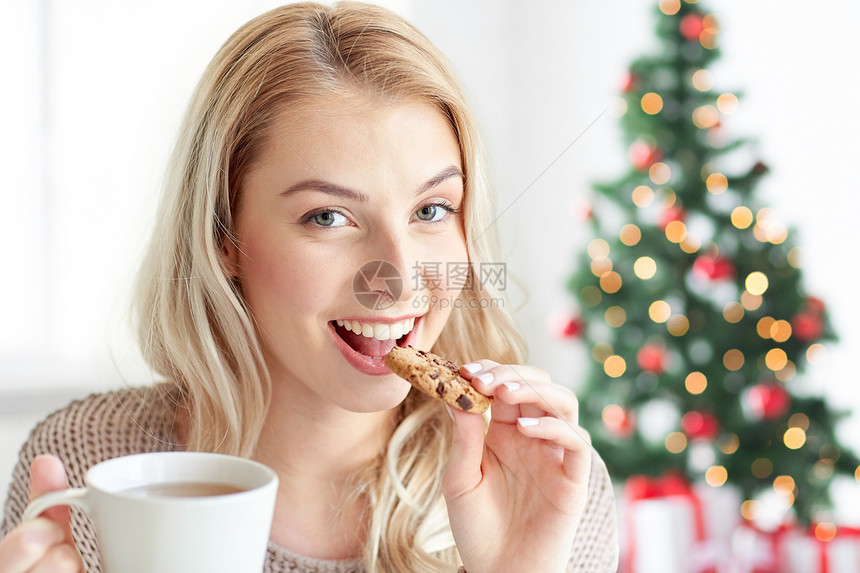 圣诞树背景快乐的女人喝咖啡吃饼干图片