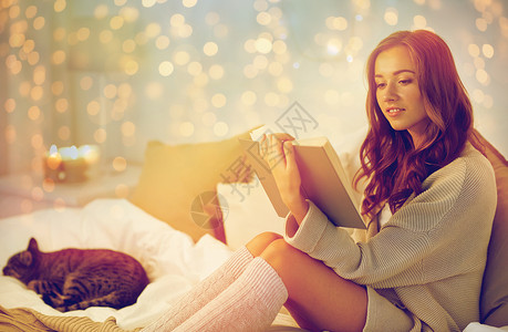 诞节,舒适,休闲人们的快乐的轻女人床上阅读书家里的卧室快乐的轻女人家床上看书背景图片