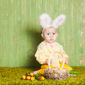 男孩和兔小男孩像复活节兔子样草地上放着五颜六色的鸡蛋复活节兔子蹒跚学步背景