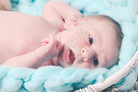 婴儿针新生婴儿蓝色的巨大钩针毯子上仰望新生儿背景