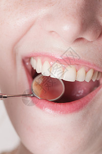 检查牙齿时,用牙科镜打开女人的嘴检查牙齿图片