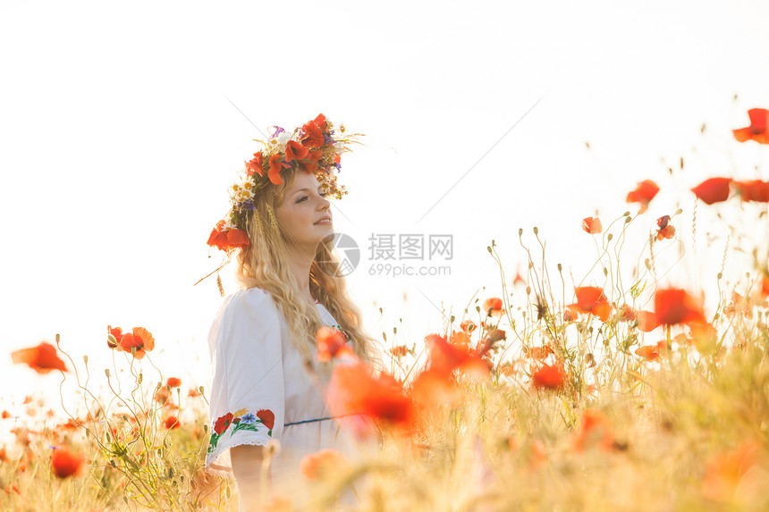 漂亮的金发女孩穿着件图案的花的连衣裙,头上戴着花环,片花的田野里享受着田里的女孩图片