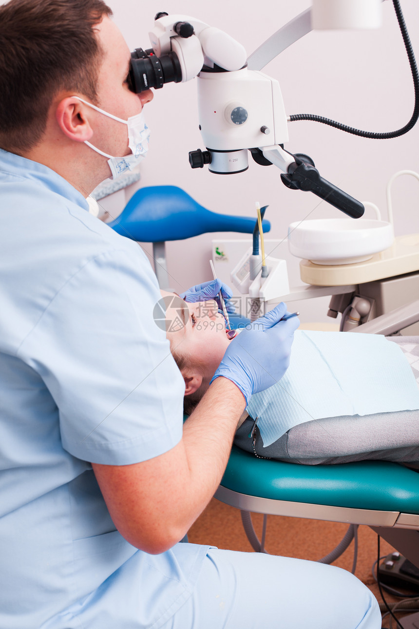 牙医透过放大镜看他牙科办公室用显微镜手术图片