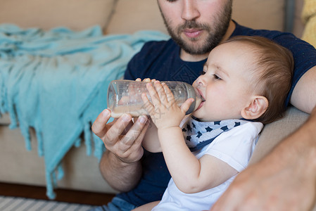 轻的父亲用奶瓶喂他的孩子图片