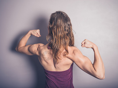 位轻的女健美运动员正摆姿势,展示她手臂中的肌肉定义图片