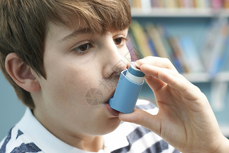 男孩用吸入器治疗哮喘发作高清图片