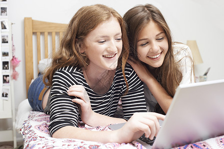 两个十几岁的女孩卧室看笔记本电脑背景图片
