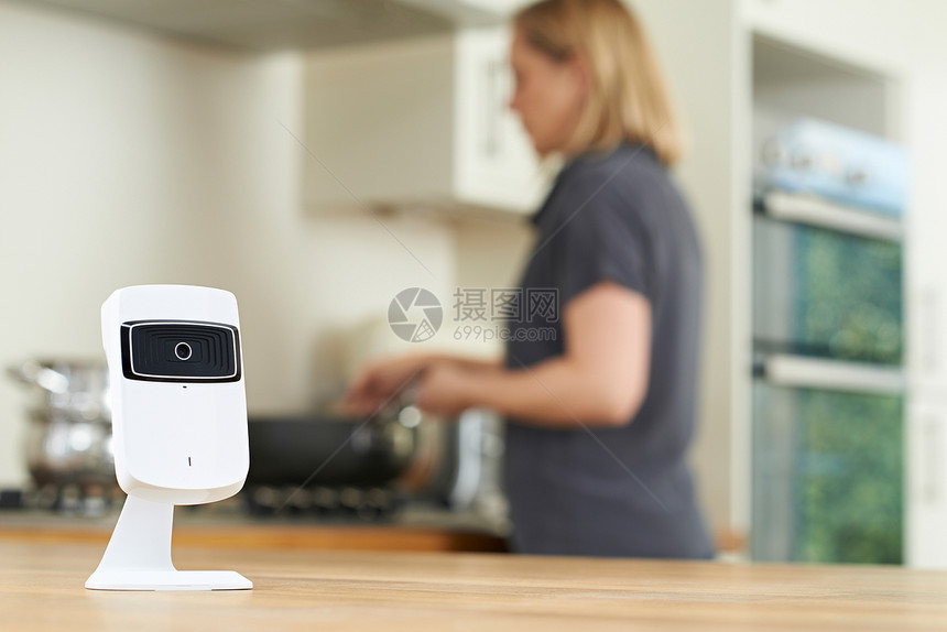 厨房里的智能安全摄像头,因为女人准备饭菜图片