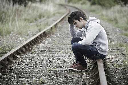 沮丧的轻人坐铁路轨道上图片