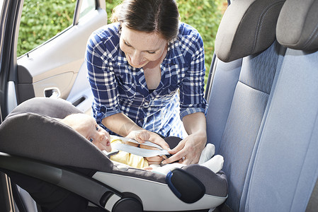 母亲把婴儿放汽车座位上旅行图片
