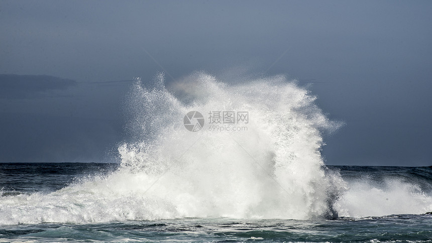 股巨大的波浪风暴河口的海岸线上撞击岩石,造成了巨大的飞溅图片