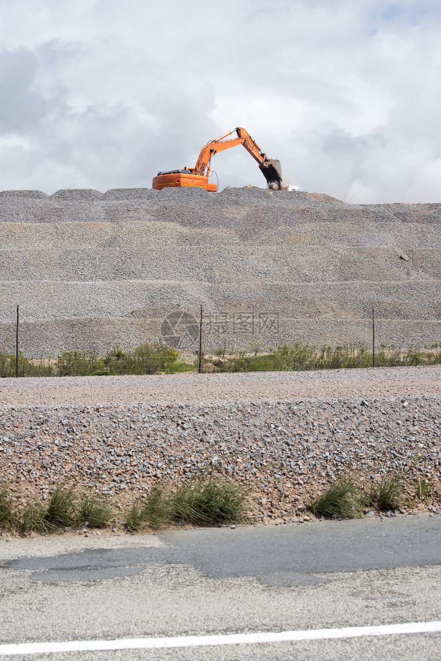 道路工程中,台大型挖掘机将砾石装载卡车上图片