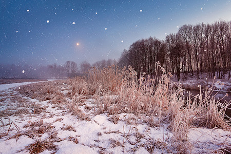 朦胧月光神奇的冬季诞夜河流上的降雪场景月光下的霜雪花背景