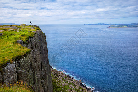 林峰光芒四射游客与背包站悬崖集市头,北爱尔兰,英国孤独的游客,背包站悬崖博览会的头上,看着拉特林岛,县安特里姆,英国背景