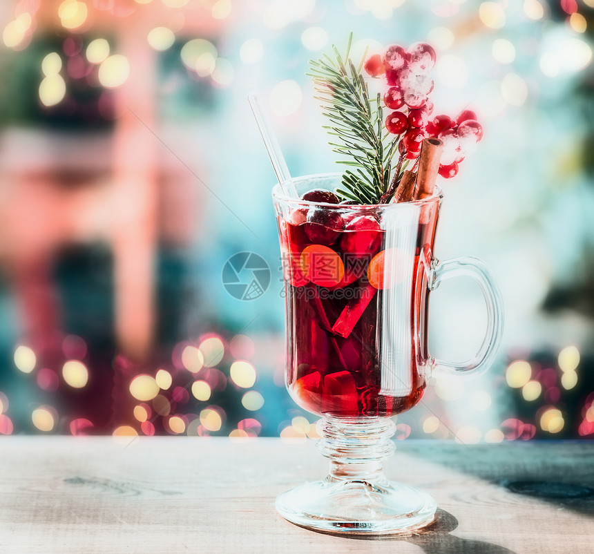 喜庆的Bokeh照明背景下,桌上杯带浆果冷杉枝的五香覆盖葡萄酒图片