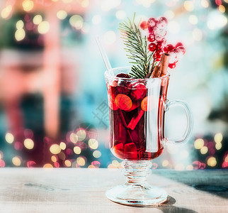 喜庆的Bokeh照明背景下,桌上杯带浆果冷杉枝的五香覆盖葡萄酒图片