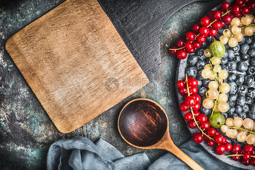 健康食谱的食物背景与各种彩色浆果,烹饪勺子,碗餐巾,顶部视图,框架图片