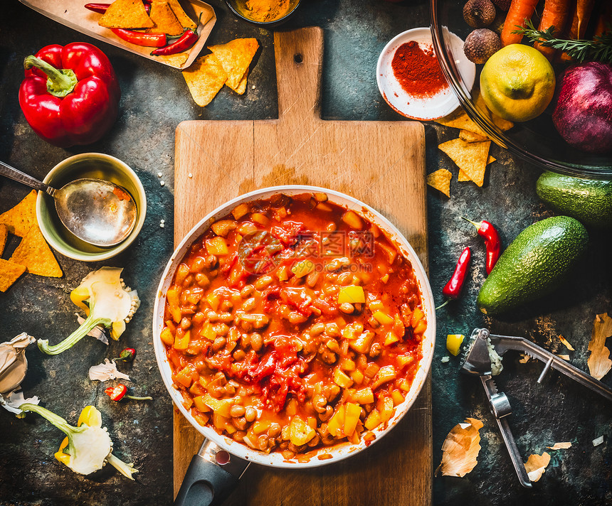素食辣椒康卡恩菜锅木制切割板与香料蔬菜烹饪配料黑暗的厨房桌子背景,顶部的视图墨西哥菜图片